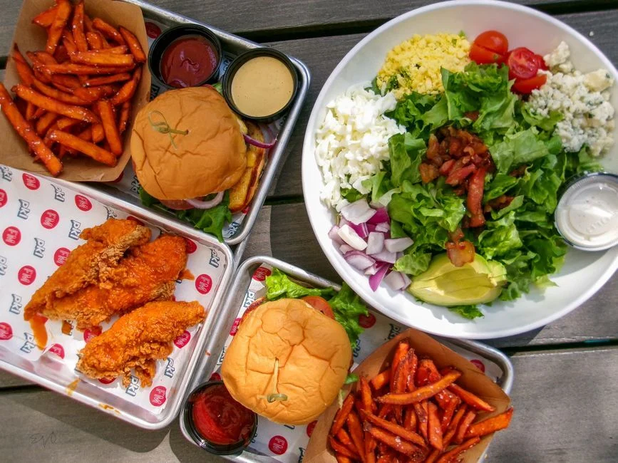 Knuspriges Fried Chicken auf Holztisch mit Sides und Saucen in Hanau